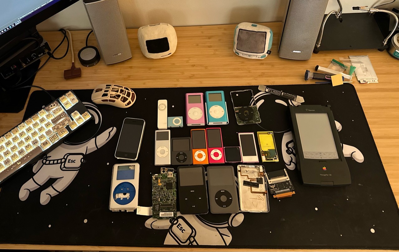 iPods of several generations on John’s workbench, including opened cases, circuit boards, and replacement parts